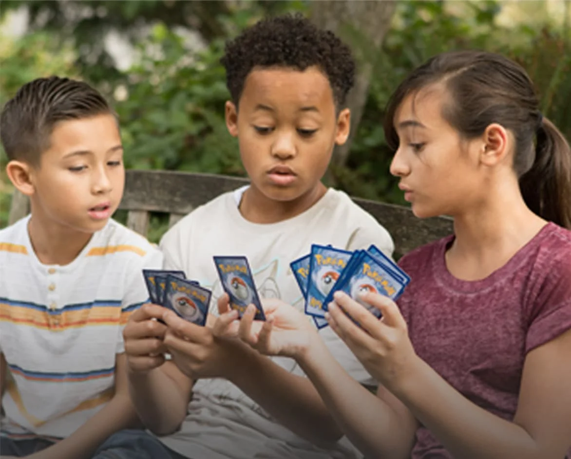 Niños jugando con cartas Pokémon y disfrutando del juego